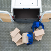 2 men in blue loading packages into the back of a white van