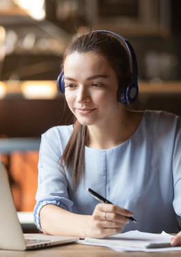 Focused woman wearing headphones using laptop in cafe