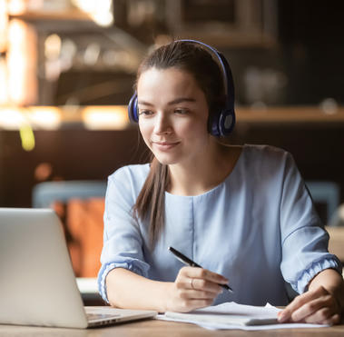 Focused woman wearing headphones using laptop in cafe